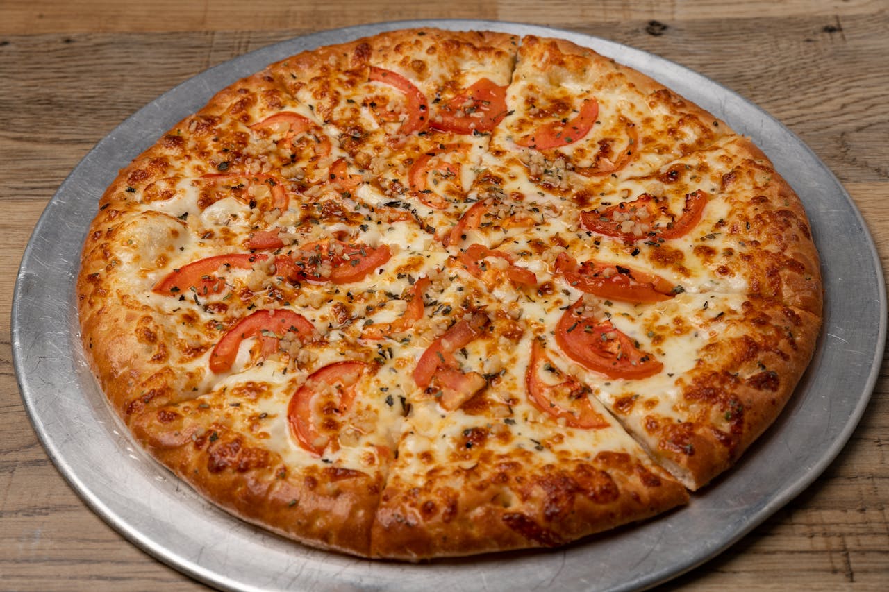 Savor a freshly baked Margherita pizza topped with ripe tomatoes and melted mozzarella cheese.