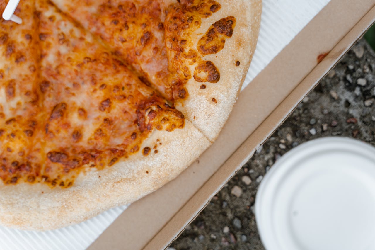 A close-up shot of a cheesy pizza slice in a cardboard box, inviting and delicious.